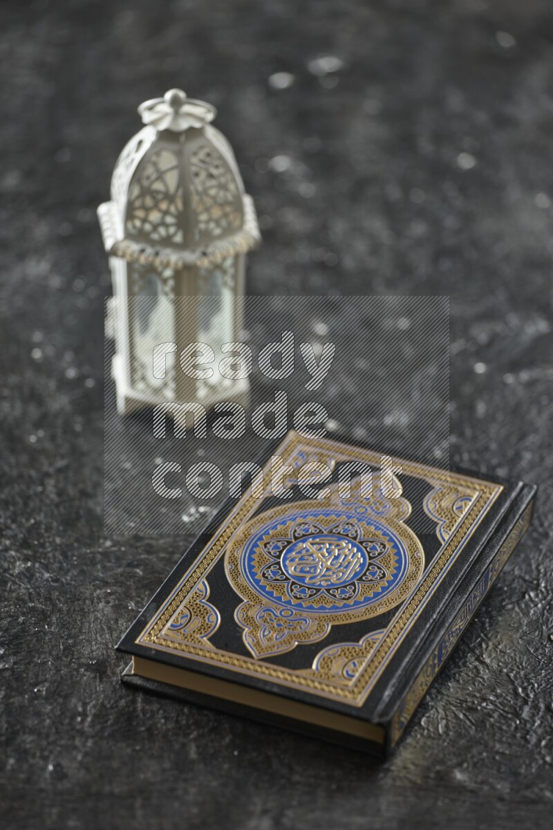 A white lantern with different drinks, dates, nuts, prayer beads and quran on textured black background