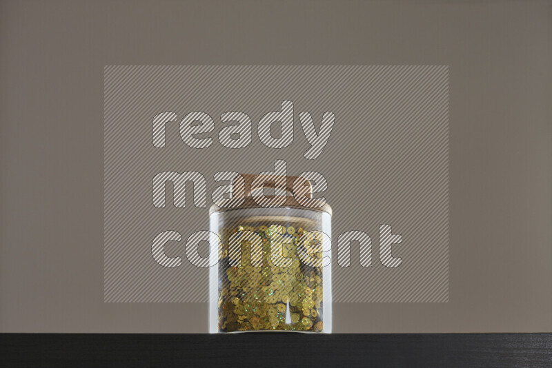 Sequins in a glass jar on black background
