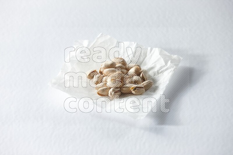 Pistachios on a crumpled piece of paper on a white background in different angles