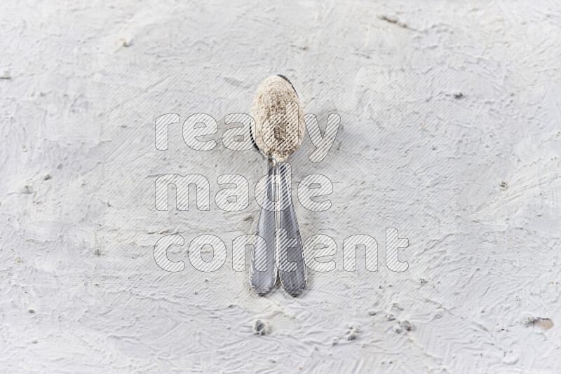 Two metal spoons full of onion powder on white background