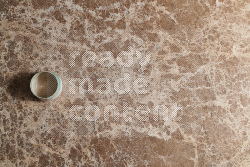 A multicolored pottery bowl on beige marble background