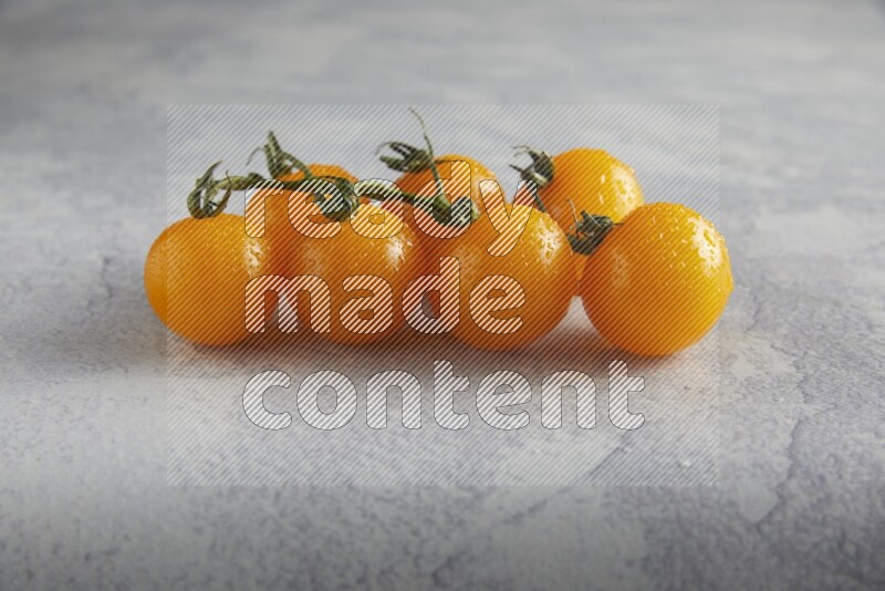 Yellow cherry tomato vein on a light grey textured background 45 degree
