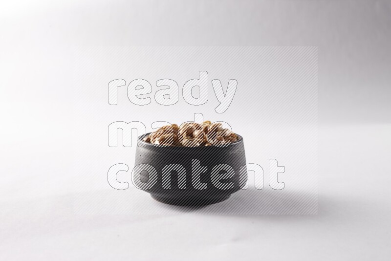 Peanuts in a black pottery bowl on white background