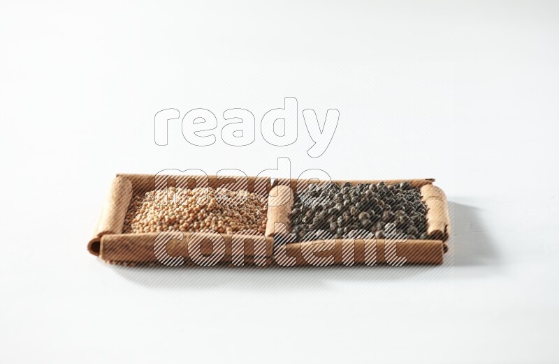 2 squares of cinnamon sticks full of mustard seeds and black peppers on white flooring