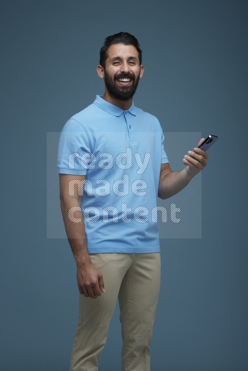Man posing with a phone in a blue background wearing a Blue shirt