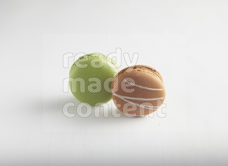 45º Shot of of two assorted Brown Irish Cream, and Green Pistachio macarons on white background