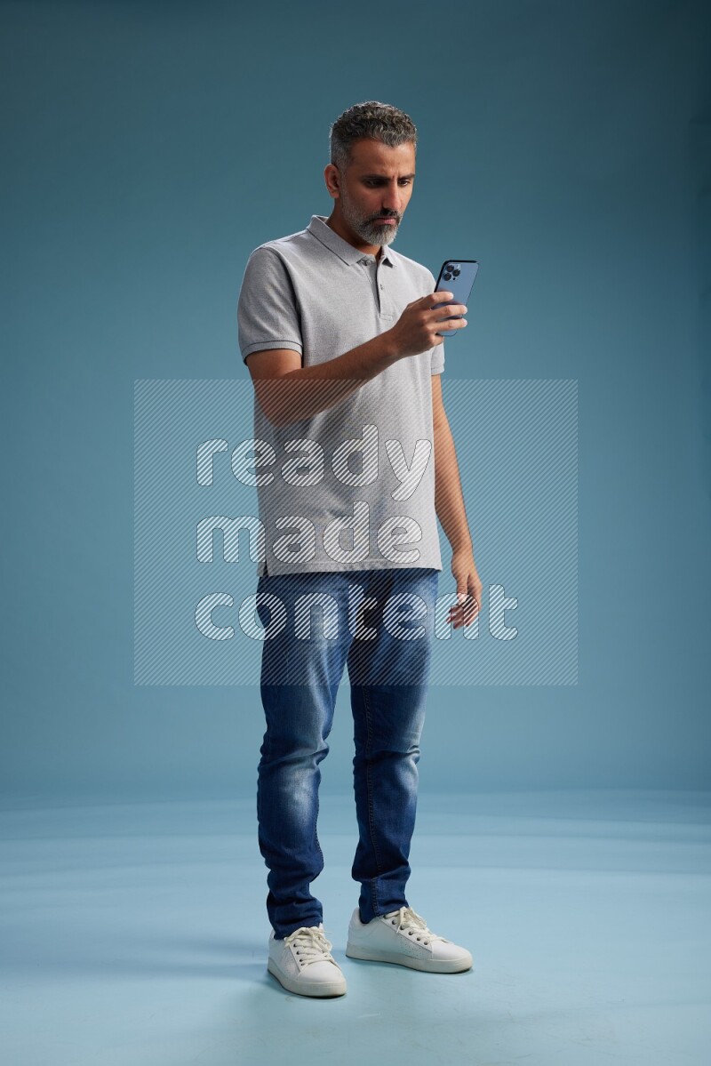 Man Standing texting on phone on blue background