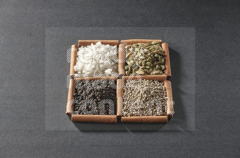 4 squares of cinnamon sticks full of black pepper, white pepper, cardamom and white salt on black flooring