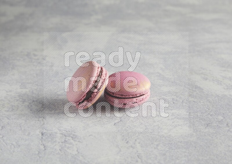 45º Shot of two Purple Strawberry macarons on white  marble background