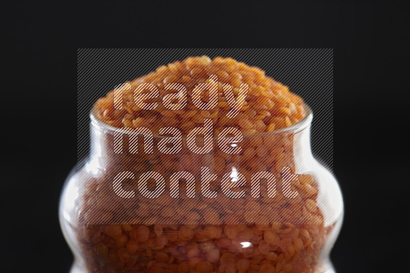 Lentils in a glass jar on black background