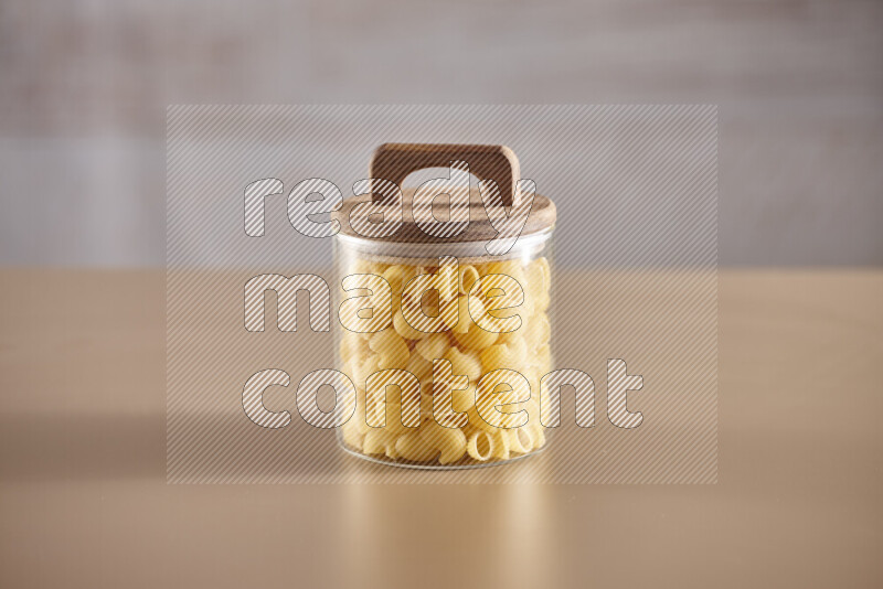 Raw pasta in glass jars on beige background