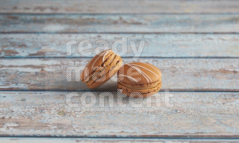 45º Shot of two Brown Irish Cream macarons on a  light blue wooden background
