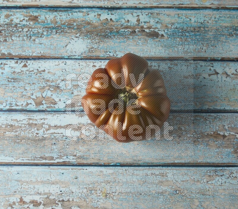 Single topview Heirloom tomato on a blue rustic wooden background