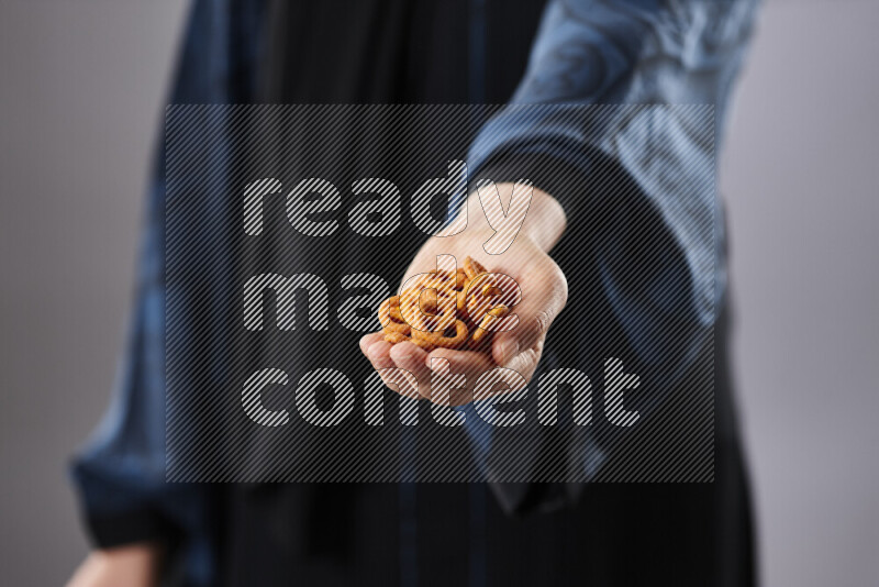Woman in abaya holding different kinds of snacks in different positions