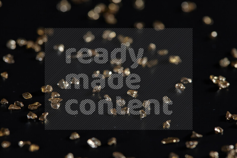 قطع زجاجية ذهبية لامعة متناثرة على خلفية سوداء