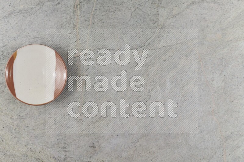 A multicolored pottery plate on grey marble background