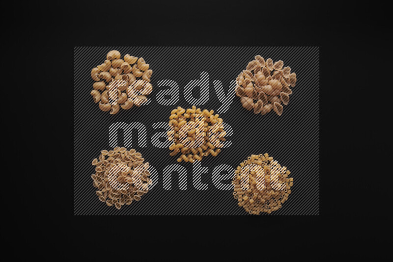 Different pasta types in bunches on black background