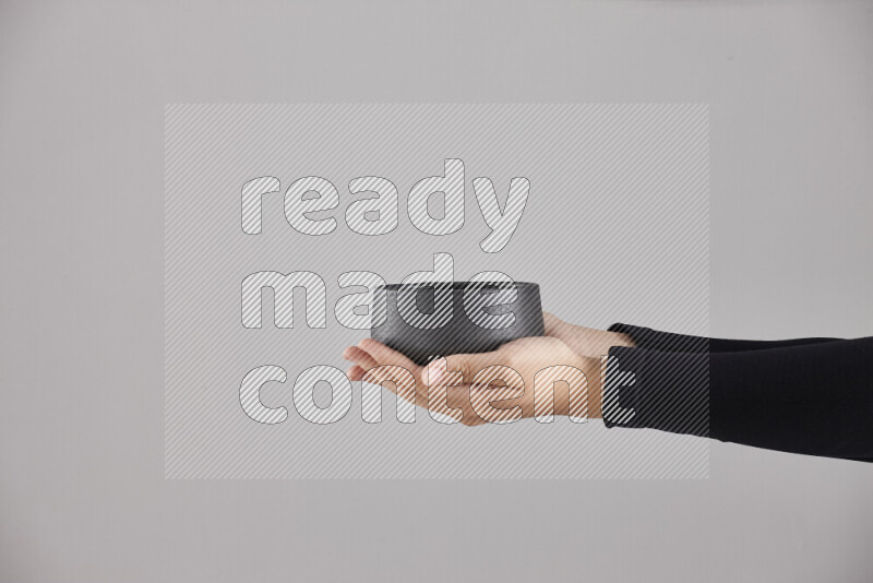 A woman in black abaya holding different pottery essentials in different positions