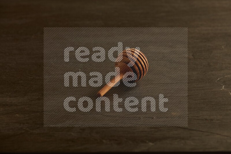 Wooden honey dipper on black slate background