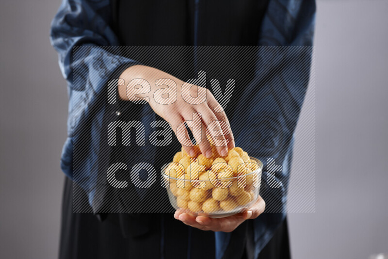 Woman in abaya holding different kinds of snacks in different positions