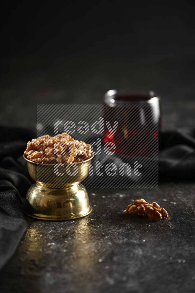 Nuts in a metal bowl with hibiscus and a napkin in a dark setup