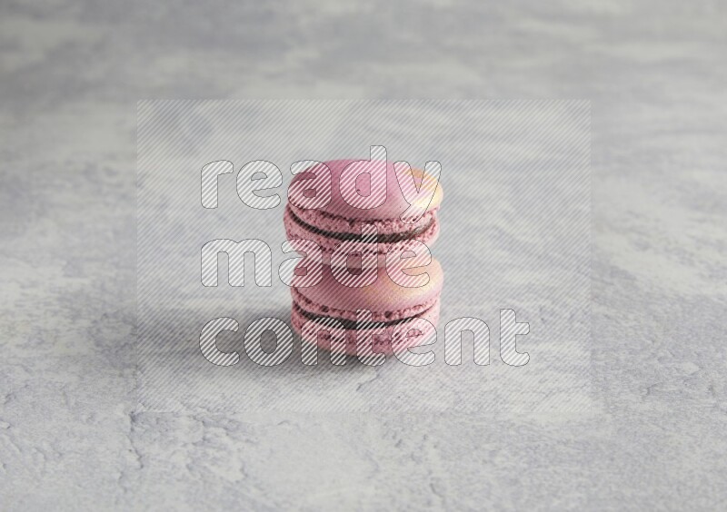 45º Shot of two Purple Strawberry macarons on white  marble background