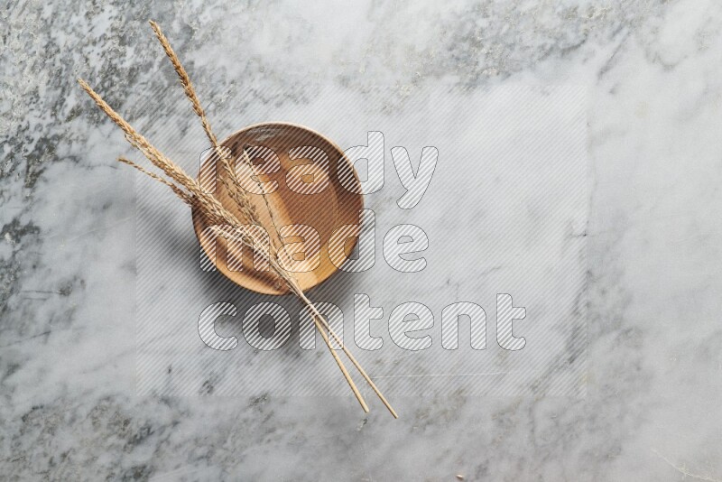 Wheat stalks on multicolored pottery plate on grey marble background