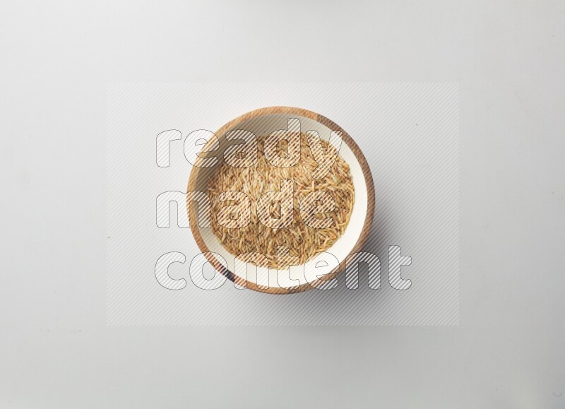 Top-view shot of long grain brown rice in a container on white background
