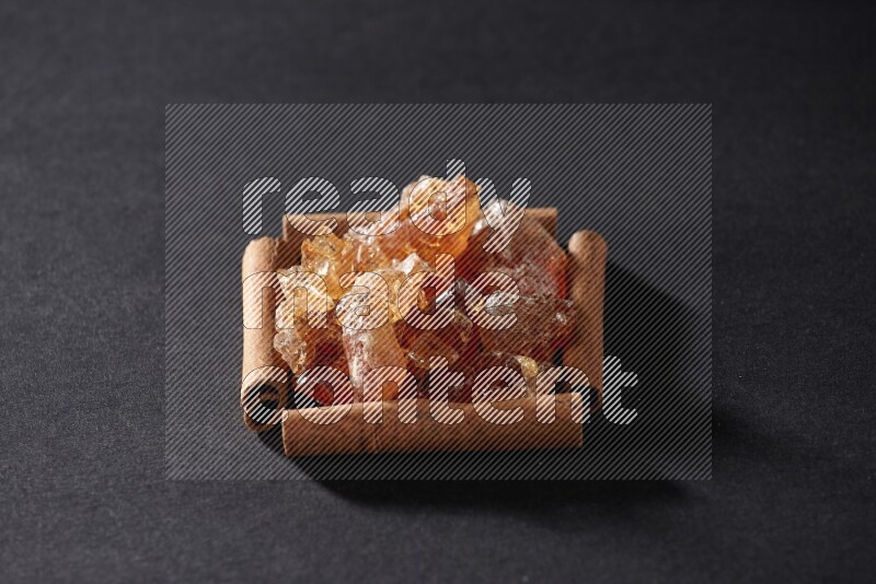 A single square of cinnamon sticks full of Arabic gum on black flooring