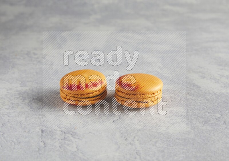 45º Shot of two orange Exotic macarons on white  marble background