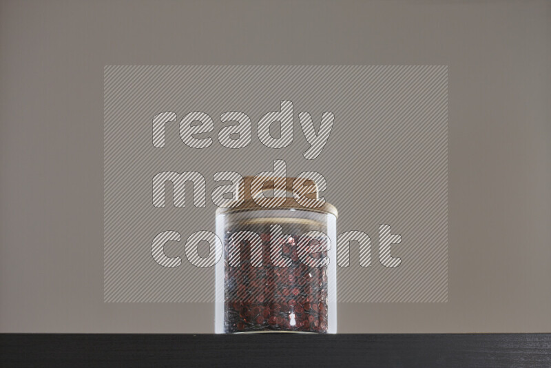 Sequins in a glass jar on black background