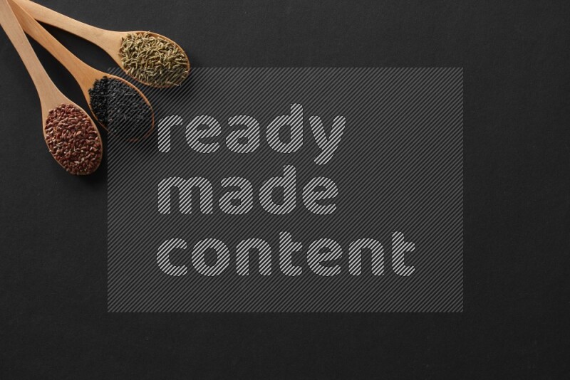 الفلفل الأسود وحبوب الخردل وحبة البركة وحب الرشاد والكمون و حبوب الكتان في معالق خشبية علي خلفية سوداء