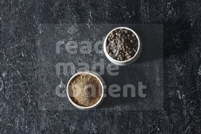 2 beige bowls, one full of allspice powder and the other full of whole balls on a textured black flooring