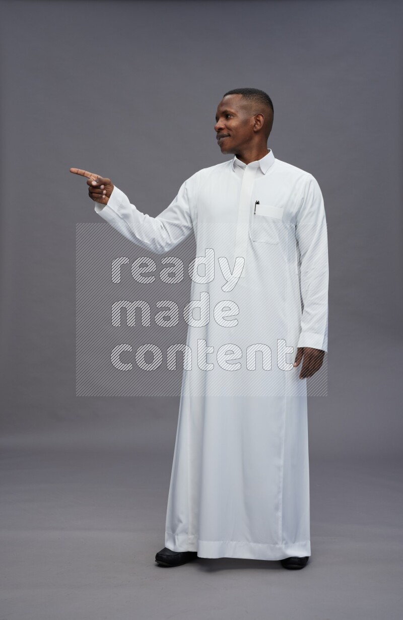 Saudi man wearing thob standing interacting with the camera on gray background