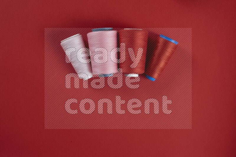 A pink and red collection of sewing and tailoring tools arranged on a red background