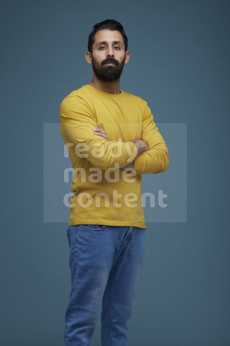 Man posing in a blue background wearing a yellow shirt