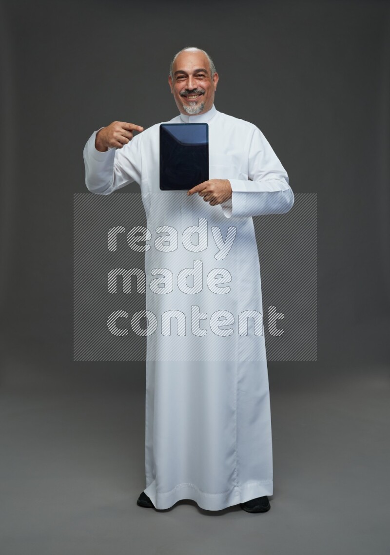 Saudi man without shomag Standing working on tablet on gray background