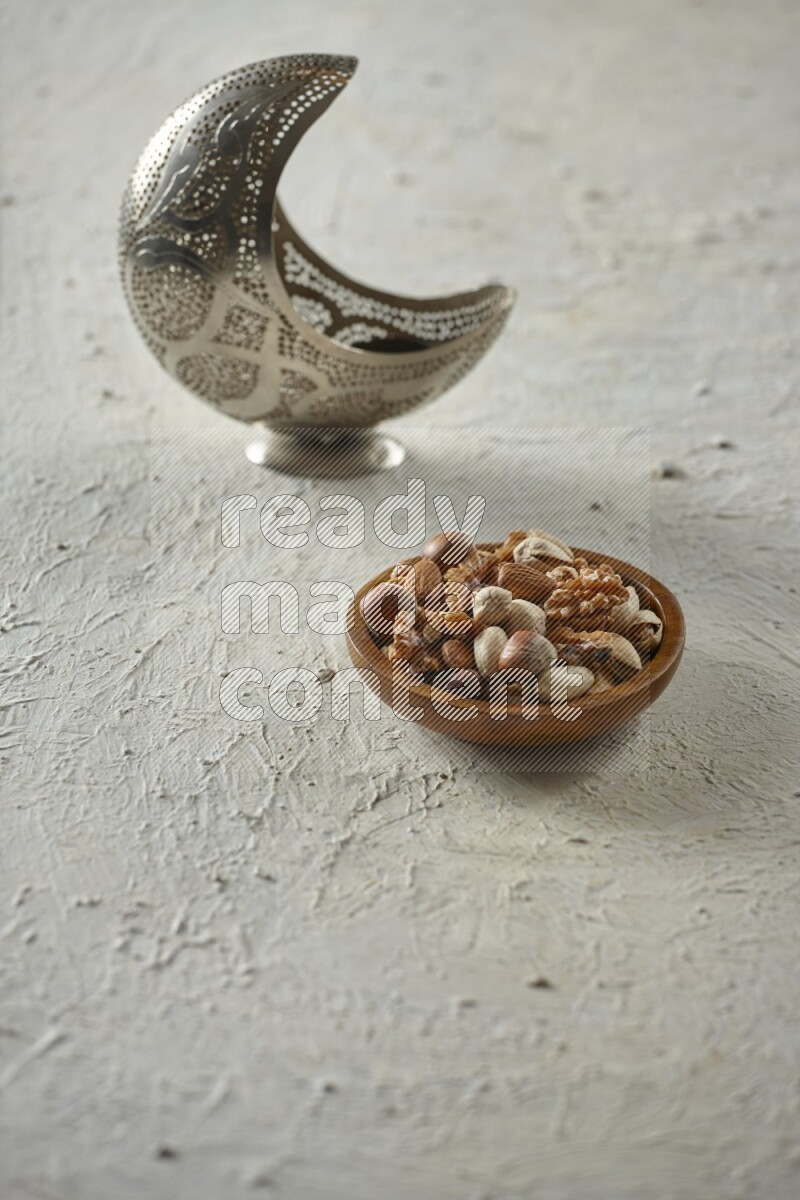 A silver lantern with different drinks, dates, nuts, prayer beads and quran on textured white background
