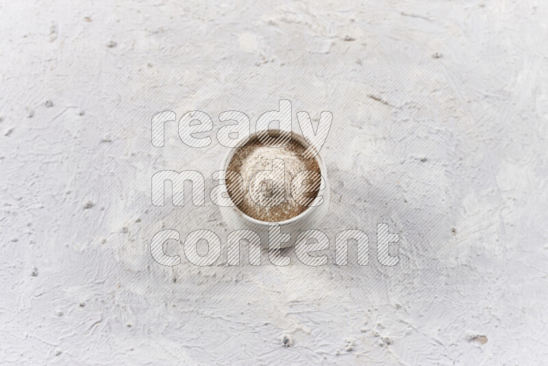 A beige pottery bowl full of onion powder on white background