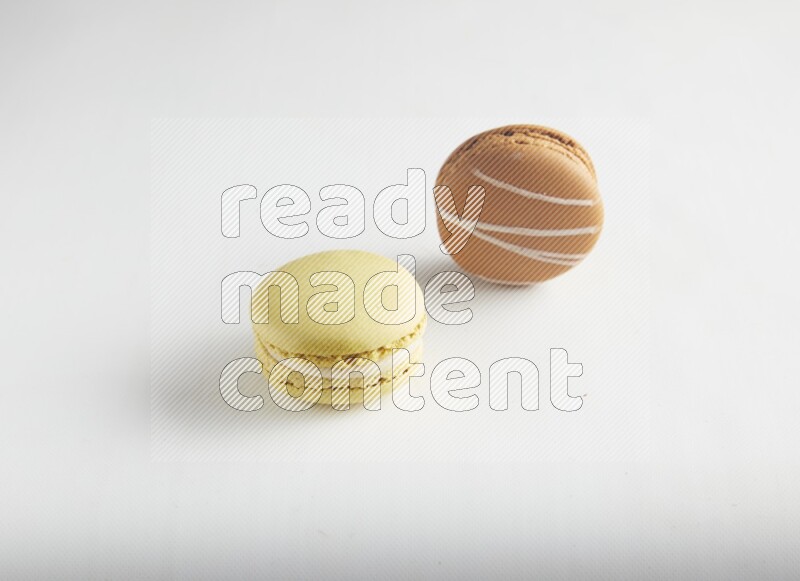 45º Shot of of two assorted Brown Irish Cream, and Yellow Lime macarons on white background