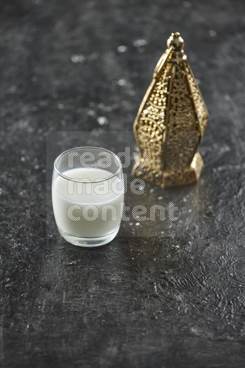 A golden lantern with different drinks, dates, nuts, prayer beads and quran on textured black background