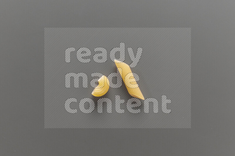 Elbow pasta with other types of pasta on grey background