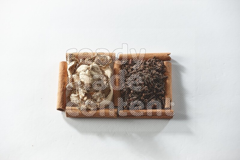 2 squares of cinnamon sticks full of cloves and dried ginger on white flooring