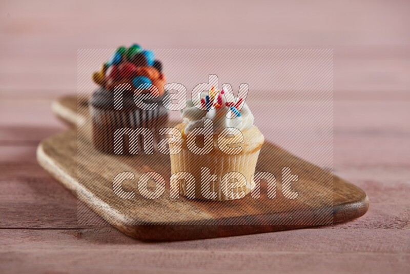 Vanilla mini cupcake topped with cream on a wooden board