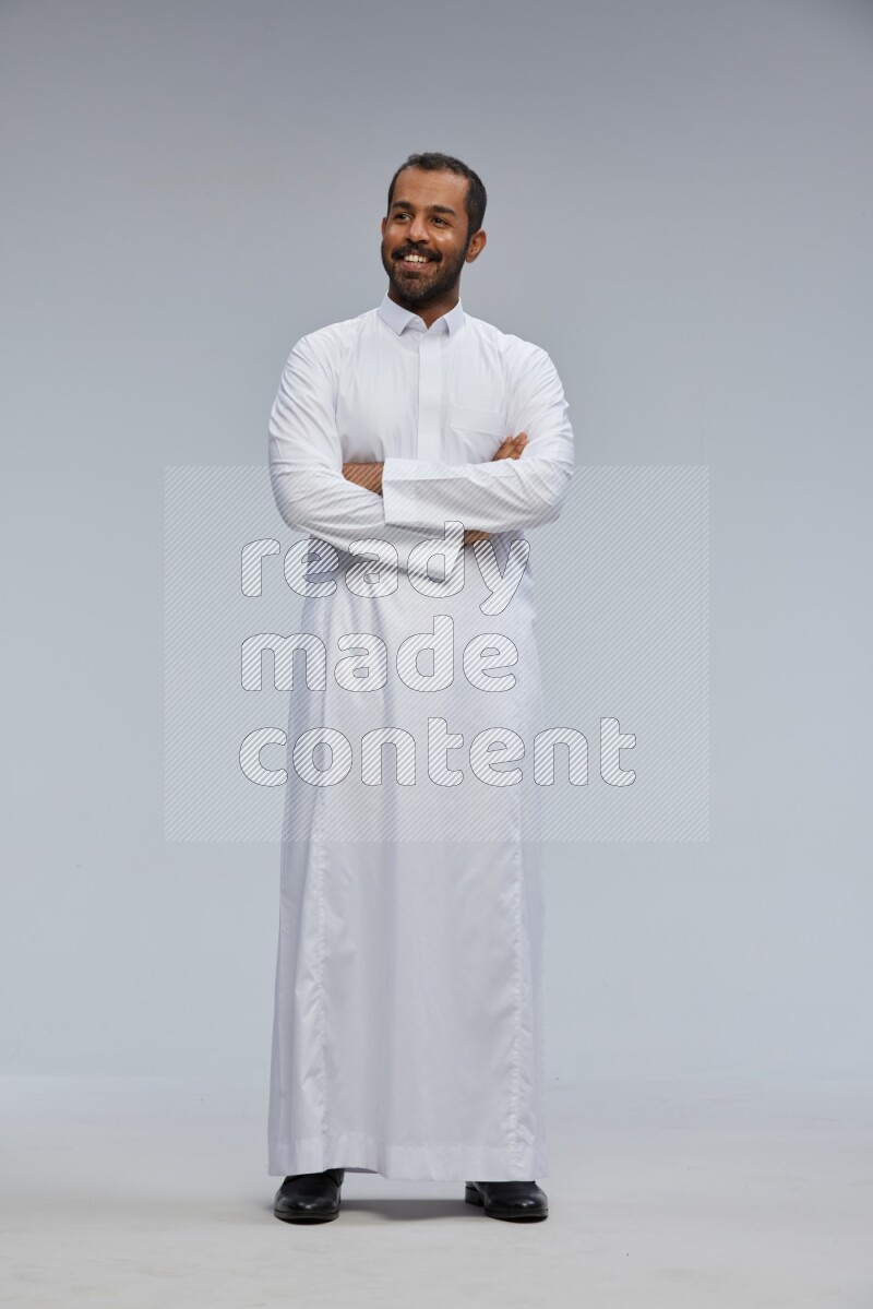 Saudi man wearing Thob standing with crossed arms on Gray background