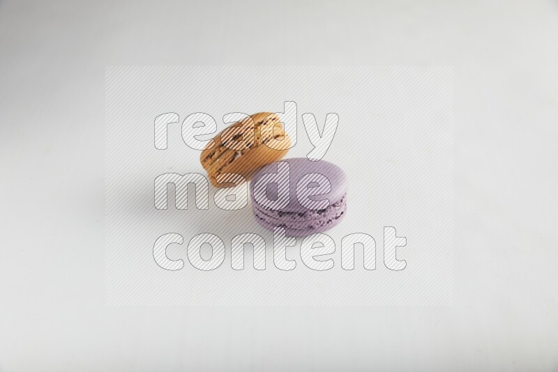 45º Shot of of two assorted Brown Irish Cream, and Purple Blueberry macarons on white background