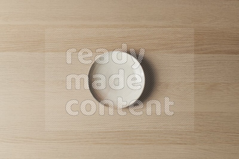 A beige pottery plate on light wooden background