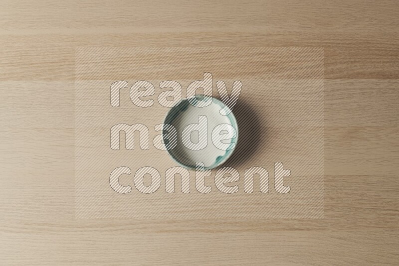 A multicolored pottery bowl on light wooden background