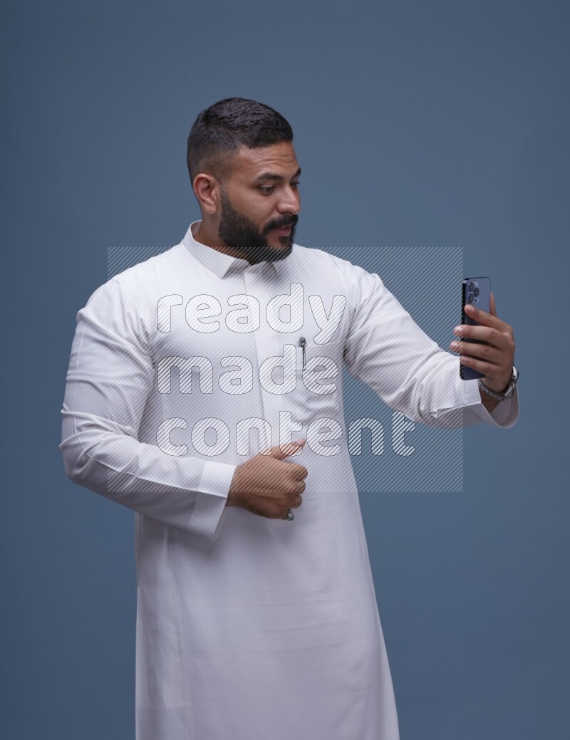 A Saudi man Taking A Selfie on Blue Background wearing Saudi Thob