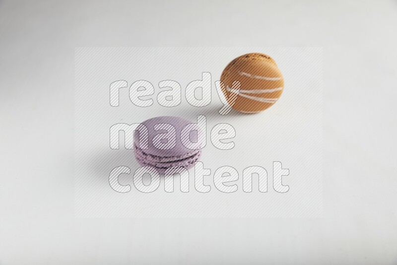 45º Shot of of two assorted Brown Irish Cream, and Purple Blueberry macarons on white background